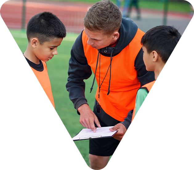 Trainer erklärt Kindern beim Fußball